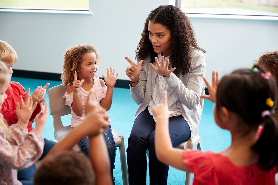 Teacher showing numbers using hands to group of young children
