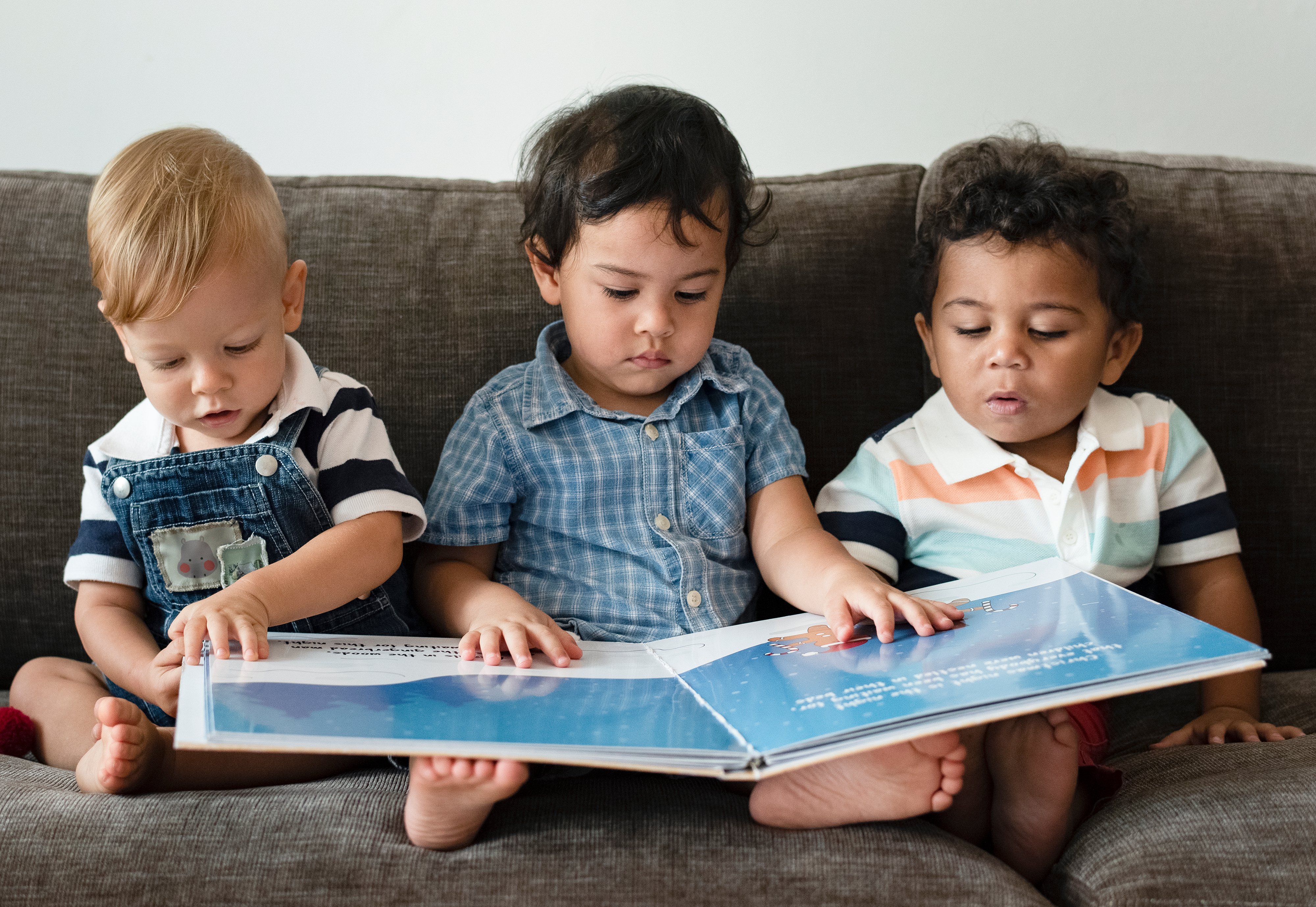 3 toddlers looking at a book