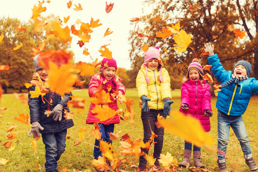 kids tossing fall leaves into the air